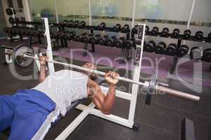 Determined muscular man lifting barbell in gym