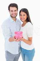 Happy couple showing their piggy bank