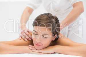 Attractive young woman receiving shoulder massage at spa center