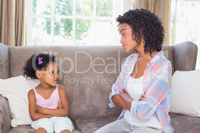 Pretty mother sitting on couch with petulant daughter
