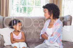 Pretty mother sitting on couch with petulant daughter