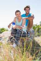 Fit couple taking a break at summit smiling at camera