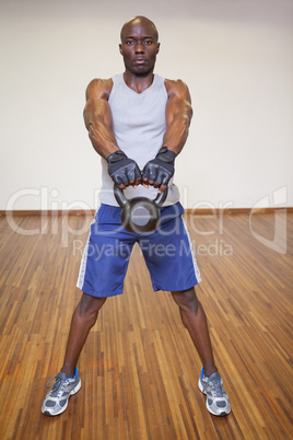 Muscular man exercising with kettle bell in gym