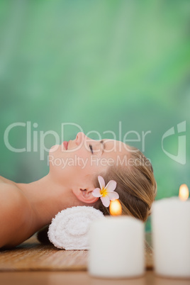 Peaceful blonde lying on bamboo mat with candles