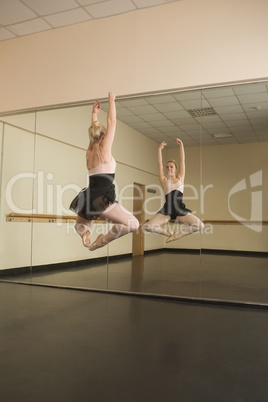 Beautiful ballerina dancing in front of mirror