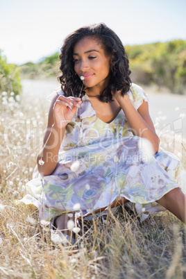 Happy pretty woman sitting on the grass in floral dress