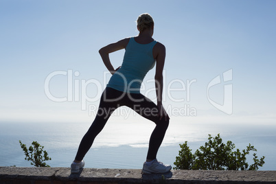 Fit woman stretching her legs looking out to sea