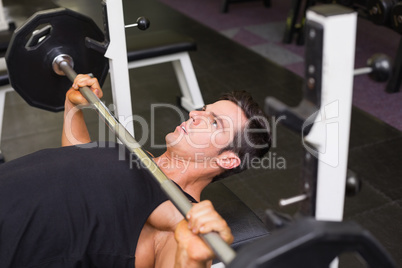 Determined muscular man lifting barbell