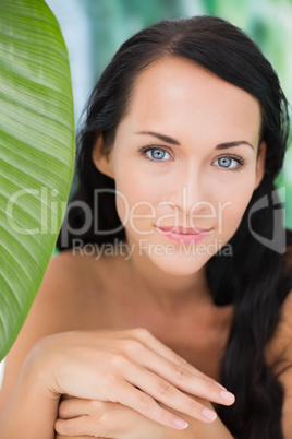 Beautiful nude brunette smiling at camera with green leaf