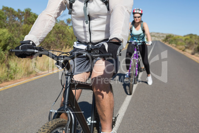 Active happy couple going for a bike ride in the countryside
