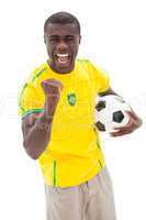 Excited brazilian football fan cheering holding ball