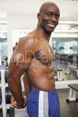 Smiling shirtless muscular man in gym