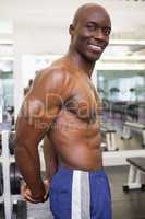 Smiling shirtless muscular man in gym