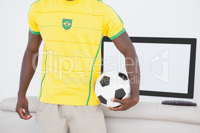 Brazilian fan holding ball in front of tv