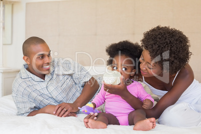 Happy parents with baby girl on their bed