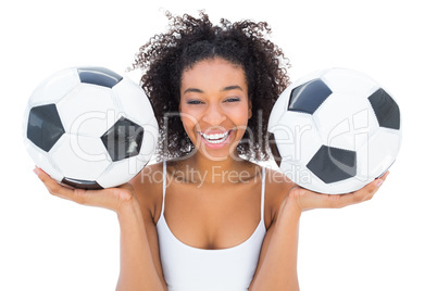 Pretty girl holding footballs and laughing at camera
