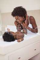 Happy mother with baby girl on changing table