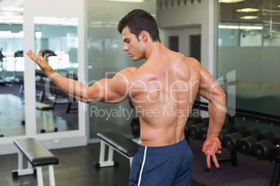 Shirtless bodybuilder posing in gym