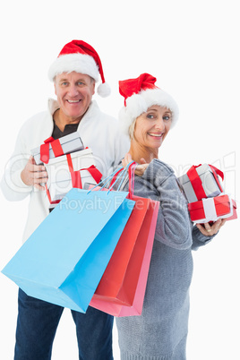 Festive mature couple in winter clothes holding gifts and bags