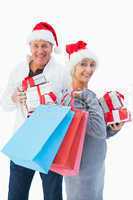 Festive mature couple in winter clothes holding gifts and bags