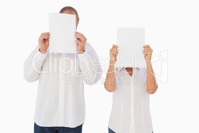 Couple holding paper over their faces