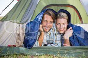 Attractive couple lying in their tent smiling at camera