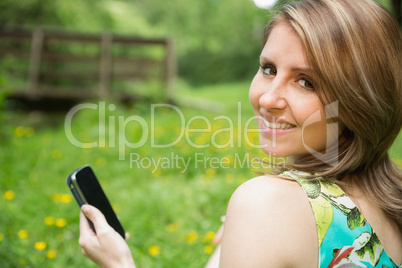 Smiling woman text messaging in field