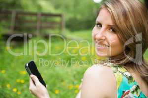 Smiling woman text messaging in field