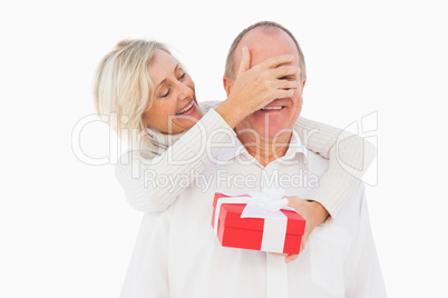 Older woman covering her partners eye while holding present
