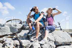 Fit cyclist couple taking a break on rocky peak