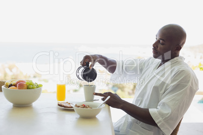 Handsome man in bathrobe having breakfast outside