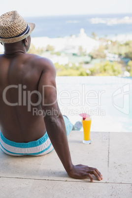 Man in swimming trunks relaxing poolside