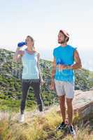 Fit couple standing drinking from water bottles