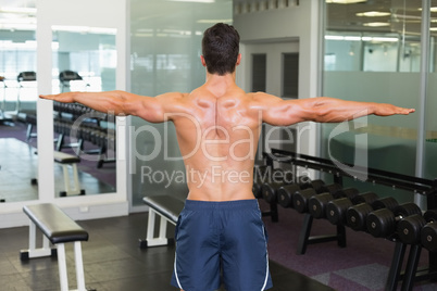 Bodybuilder with arms outstretched in gym