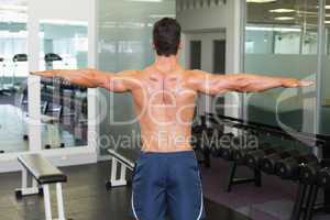 Bodybuilder with arms outstretched in gym