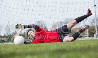 Goalkeeper in red saving a goal during a game