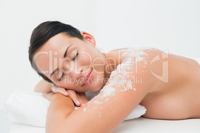 Peaceful brunette lying with salt scrub on shoulders