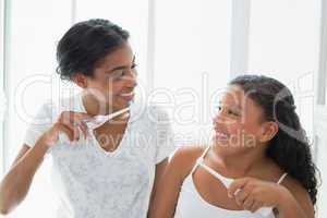 Pretty mother brushing her teeth with her daughter