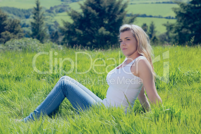 Pretty blonde thinking while sitting on grass