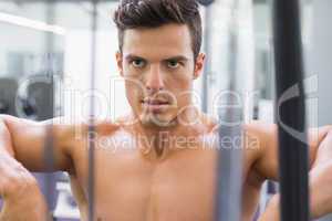 Determined shirtless young muscular man in gym