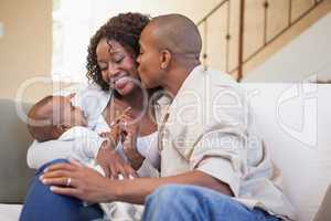 Happy parents spending time with baby on the couch