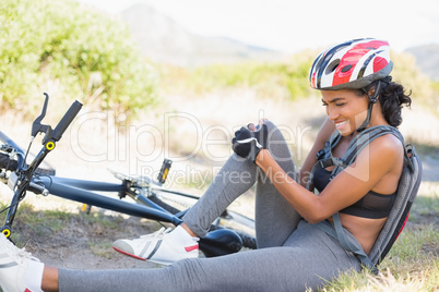 Fit woman holding her injured knee after bike crash