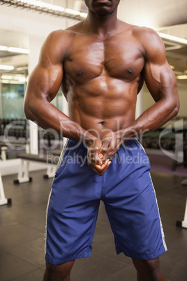 Mid section of a shirtless muscular man in gym