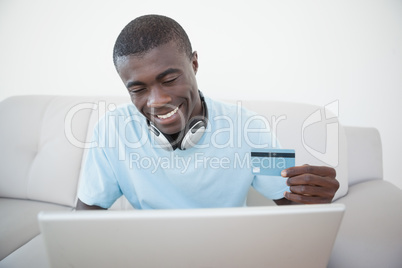 Casual man sitting on sofa using laptop to shop online