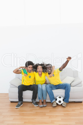 Brazil football fans sitting on couch cheering together