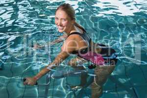 Fit happy blonde using underwater exercise bike