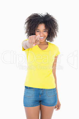 Pretty girl in yellow tshirt and denim hot pants pointing at cam