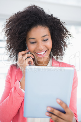 Casual businesswoman talking on phone holding tablet pc