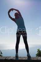 Fit woman stretching her arms looking out to sea