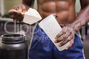 Body builder holding a scoop of protein mix